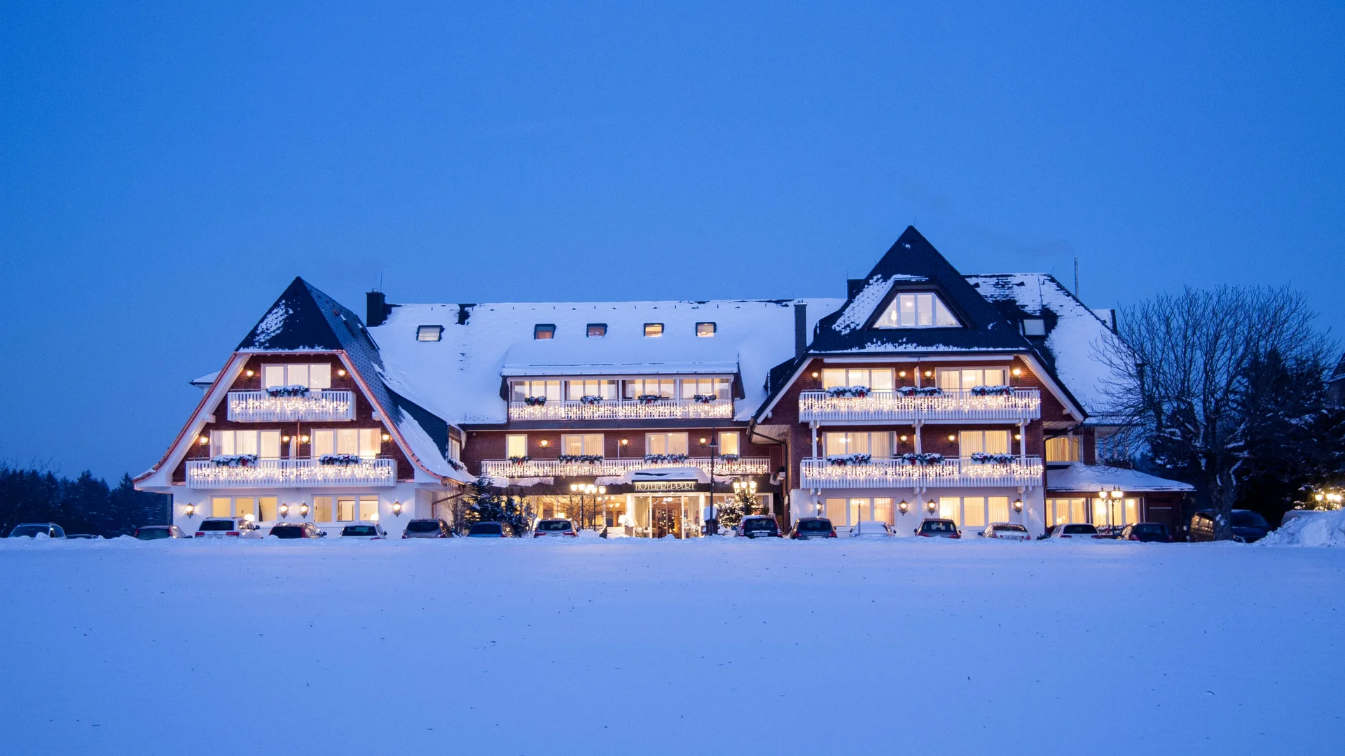Hôtel de style chalet illuminé dans un paysage enneigé au crépuscule