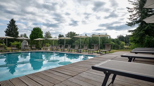 Leere Liegestühle um einen Pool an einem bewölkten Tag in der Natur