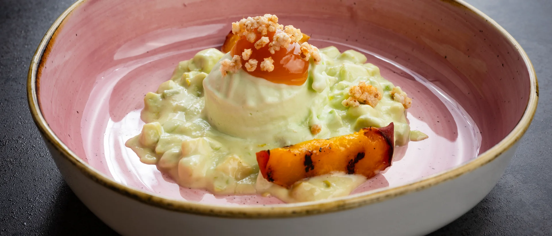 Cremiger Reis mit gegrillter Frucht und knusprigen Toppings in rosa Schüssel