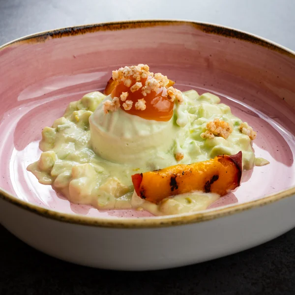 Cremiger Reis mit gegrillter Frucht und knusprigen Toppings in rosa Schüssel
