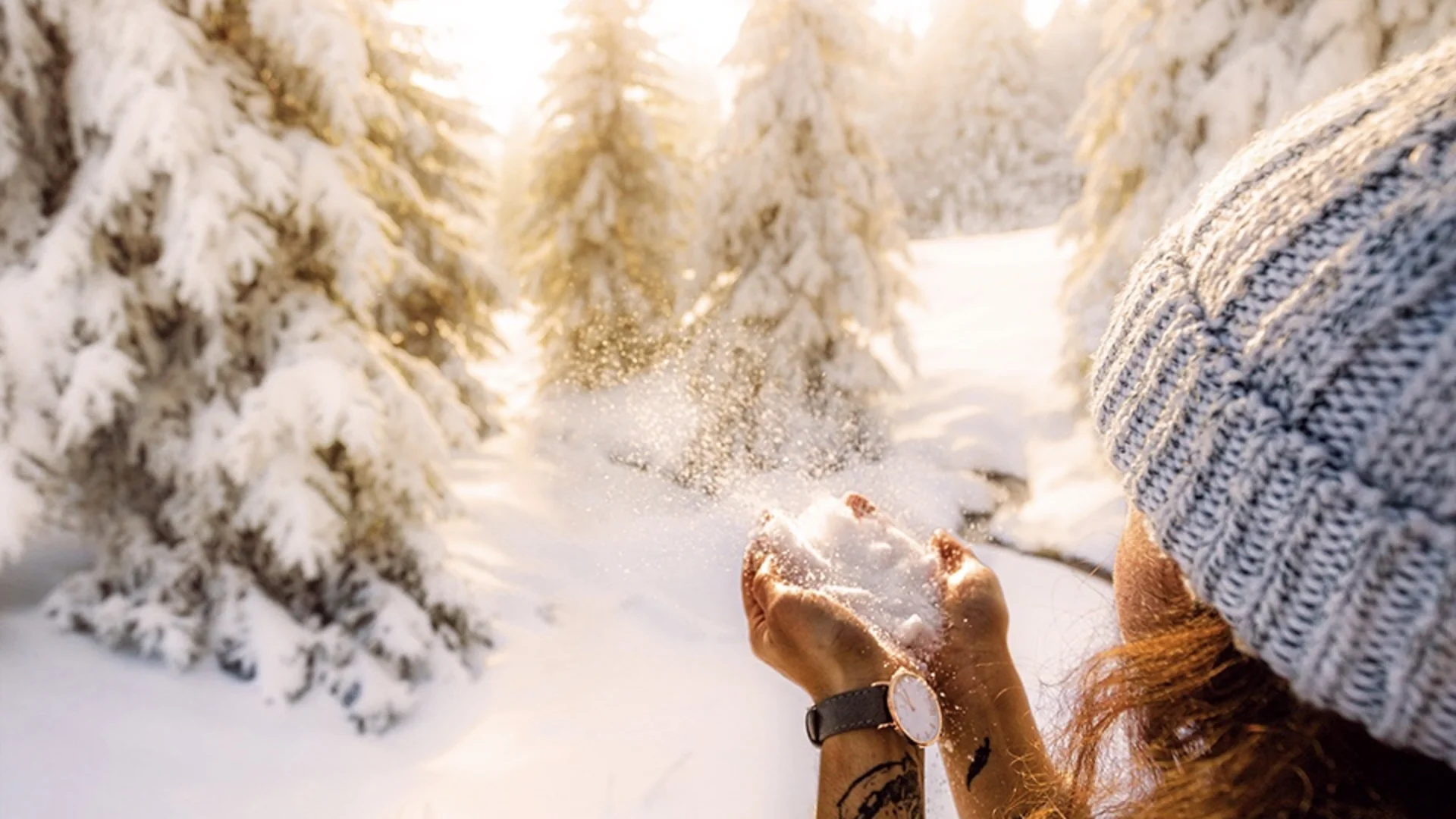 One Body, One Soul | Slow Living Hotel Reppert in Hinterzarten Woman tossing snow into the air in a sunny, snow-covered fir forest