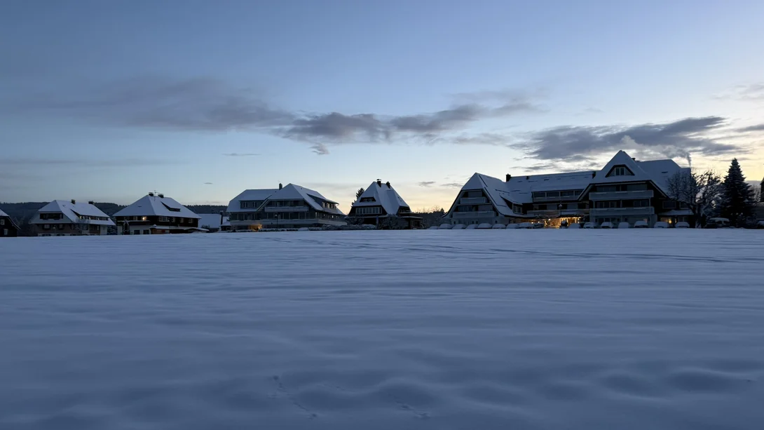 Verschneite Hotelgebäude in der Dämmerung, umgeben von einer weiten Schneefläche