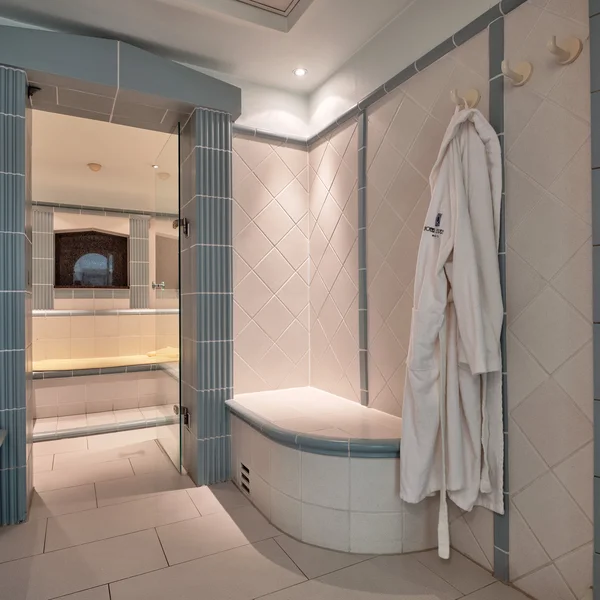 Modernes Badezimmer mit weißen und blauen Fliesen und weißem Bademantel