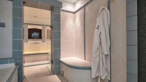 Modernes Badezimmer mit weißen und blauen Fliesen und weißem Bademantel