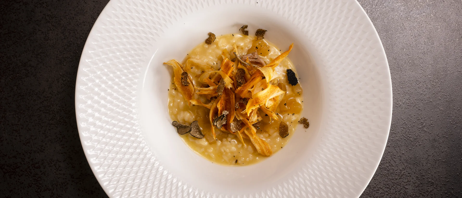 Köstliches Risotto mit Karottenchips und Trüffel auf weißem Teller