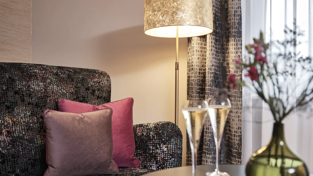 Gemütliche Ecke mit Stehlampe, Sessel und Champagnergläsern auf dem Tisch