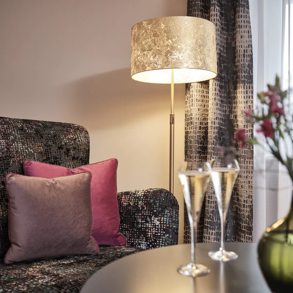 Gemütliche Ecke mit Stehlampe, Sessel und Champagnergläsern auf dem Tisch