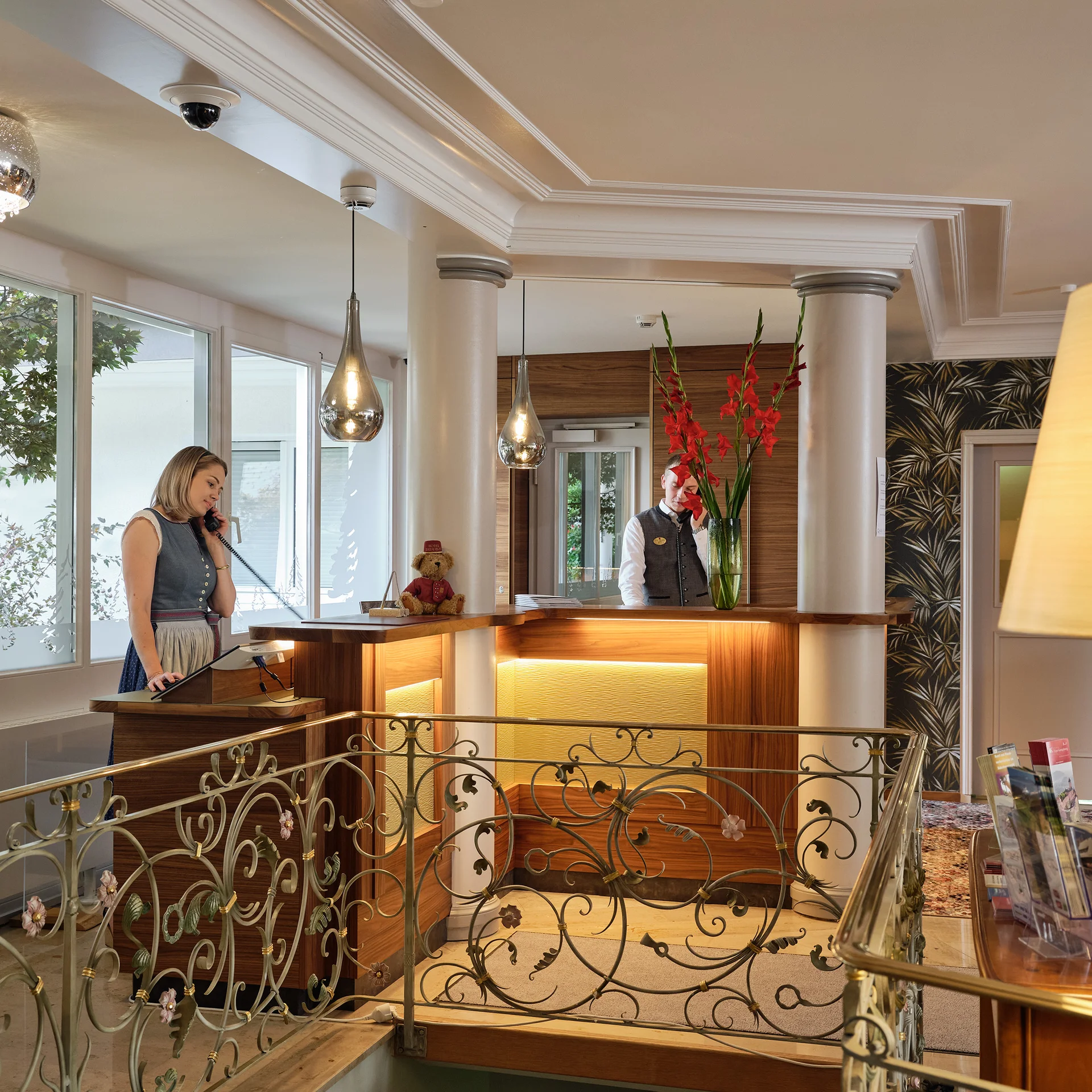 Hotelrezeption mit zwei Mitarbeitern und Blumendekor