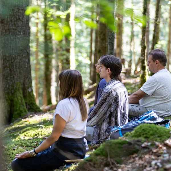 Bildergalerie | Slow Living Hotel Reppert in Hinterzarten Vier Personen sitzen entspannt im Wald auf moosbedecktem Boden