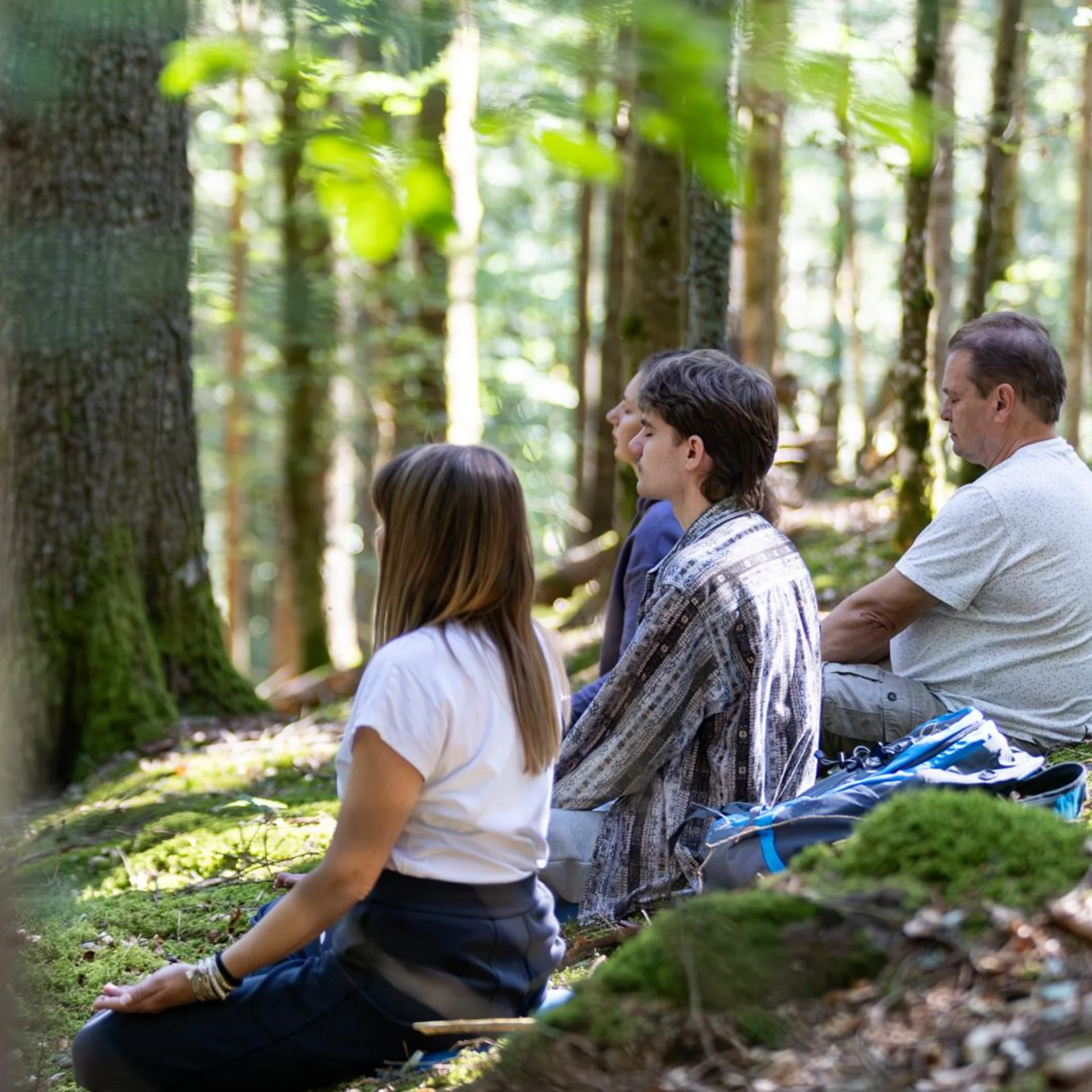One Body, One Soul | Slow Living Hotel Reppert in Hinterzarten Vier Personen sitzen entspannt im Wald auf moosbedecktem Boden