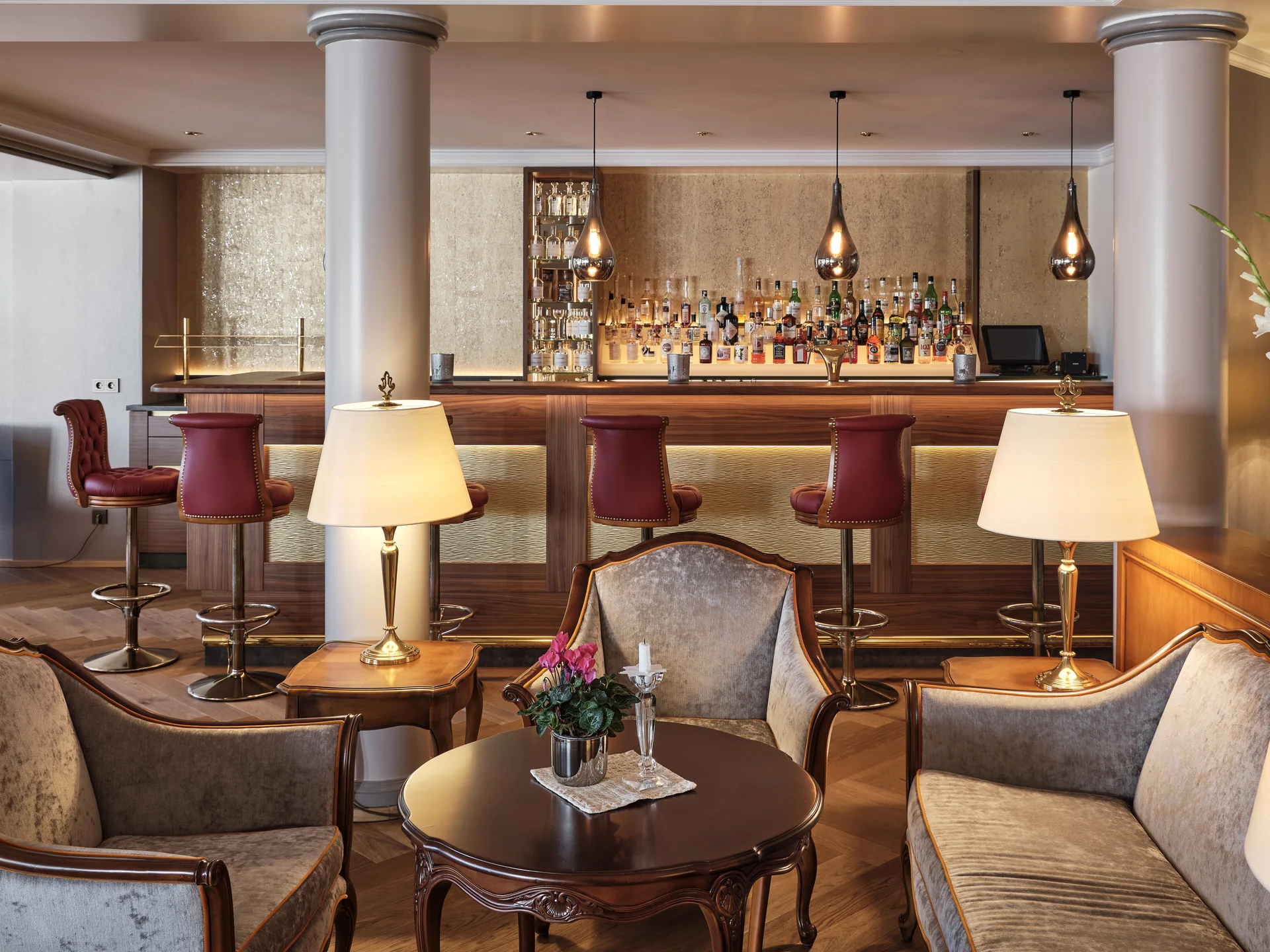 Elegante Hotelbar mit Polstersesseln, Holztisch und beleuchtetem Barbereich
