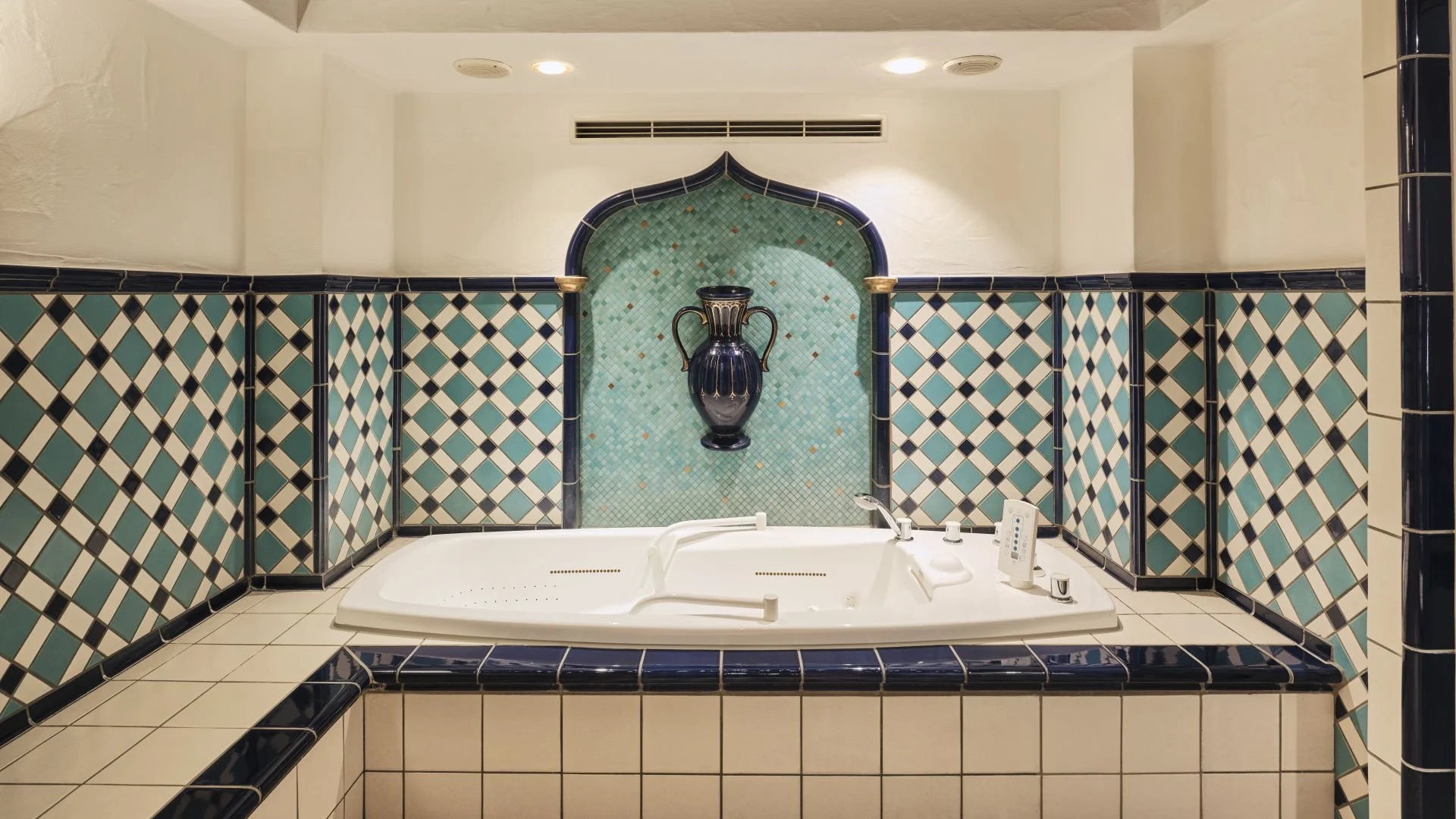 Weiß-blaue geflieste Badewanne mit einer blauen Vase an der Wand