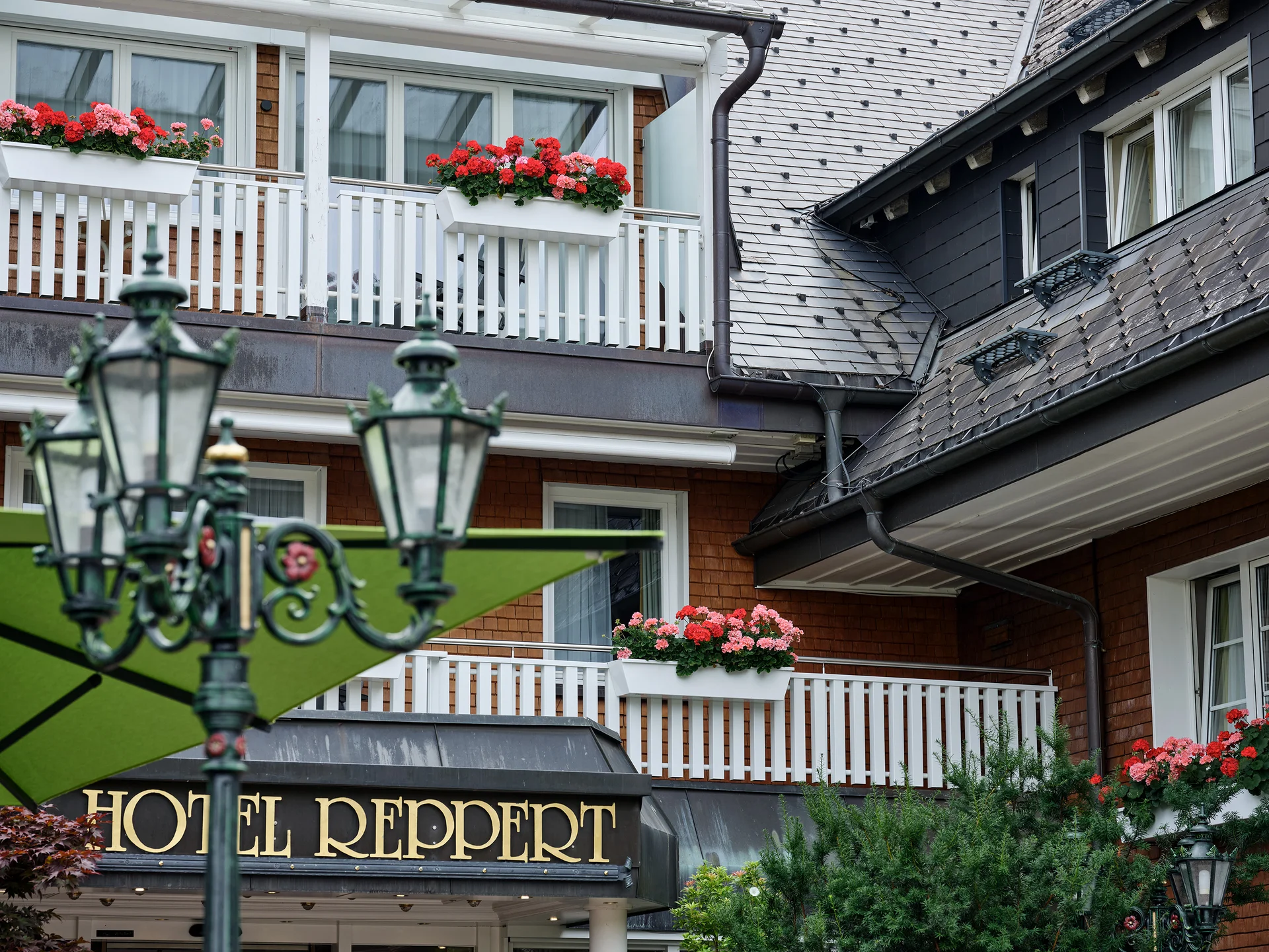 Fassade und Balkon des Hotels Reppert mit roten Blumen und Laternen