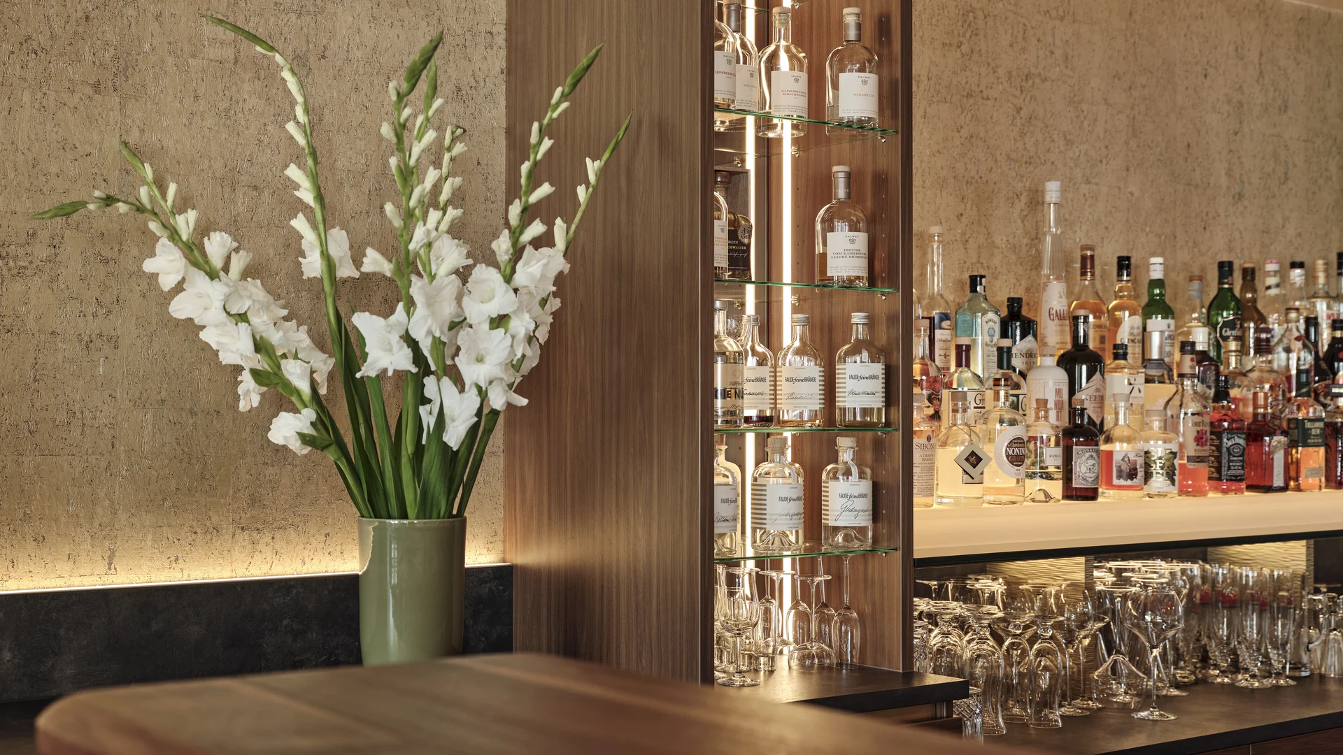 Bar mit Spirituosen, Gläsern und weißer Blumendekoration