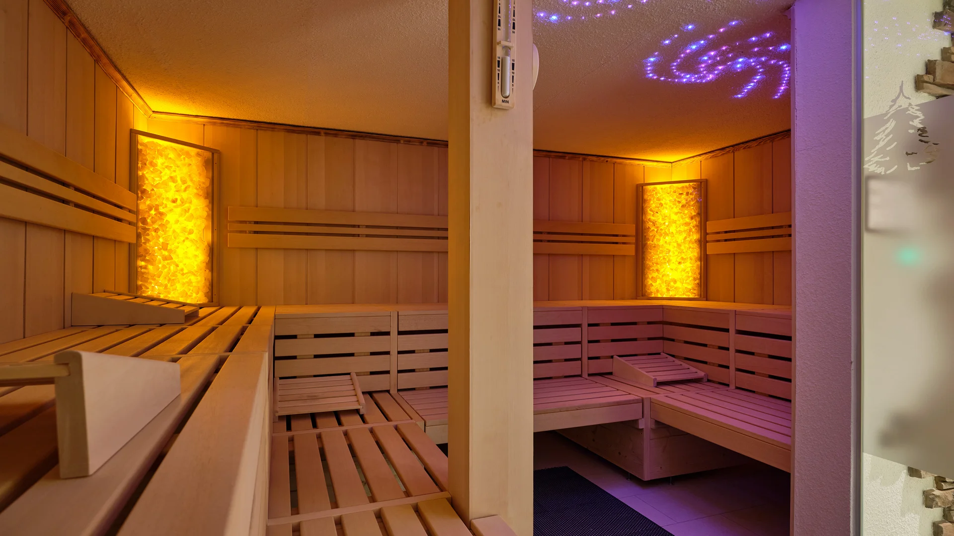 Innenraum einer Sauna mit Holzsitzbänken und beleuchteten Wänden
