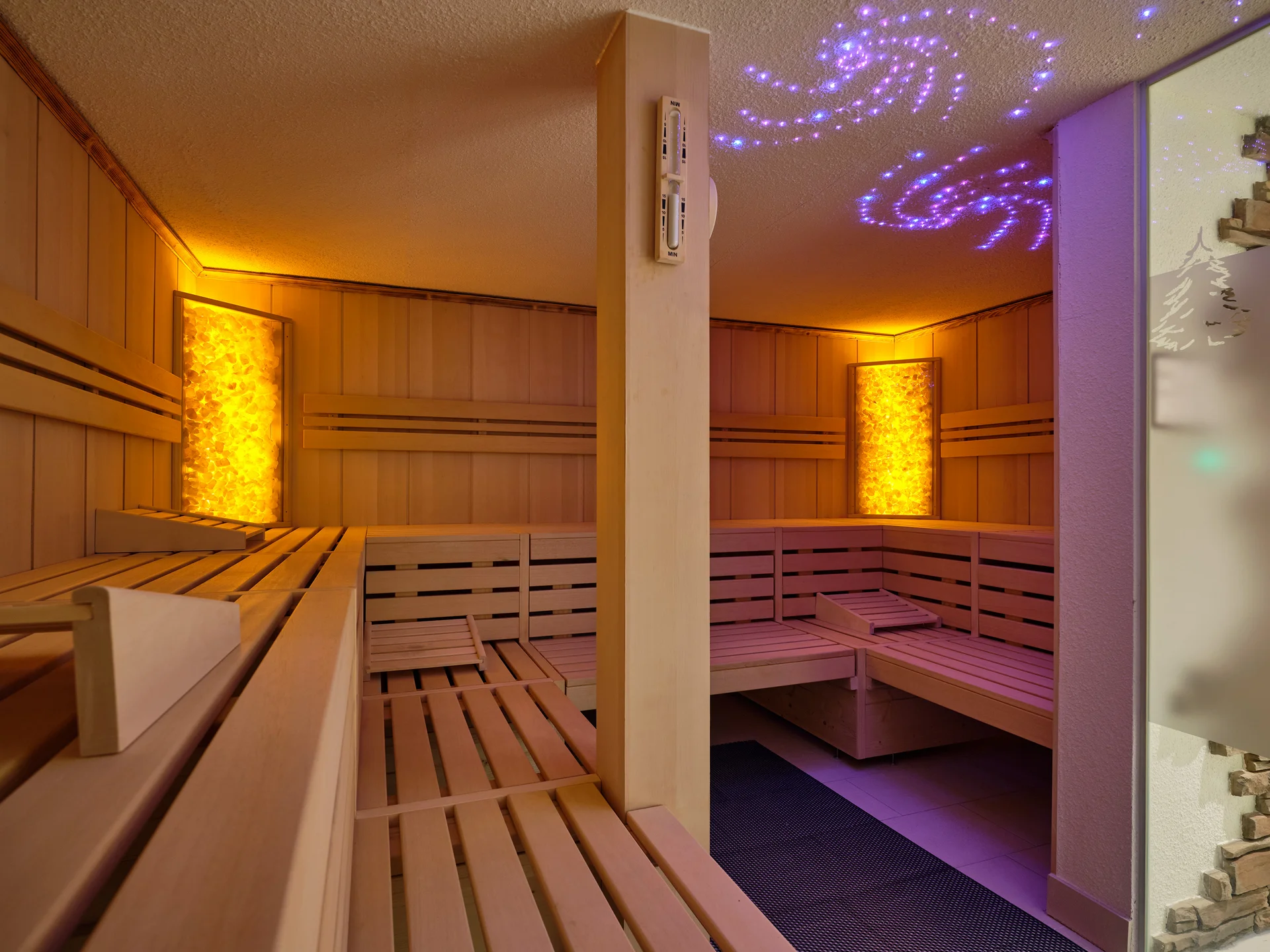 Innenraum einer Sauna mit Holzsitzbänken und beleuchteten Wänden