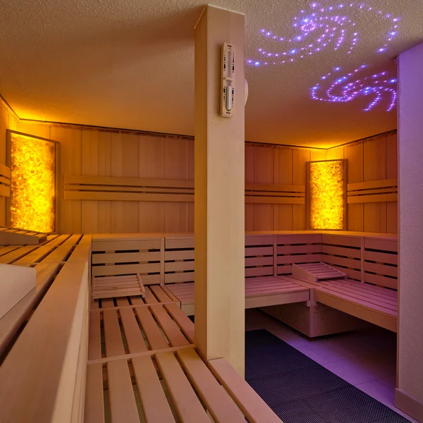 Innenraum einer Sauna mit Holzsitzbänken und beleuchteten Wänden