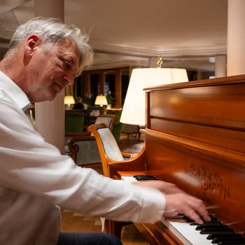 Mann spielt Klavier in elegantem Innenraum mit warmem Licht