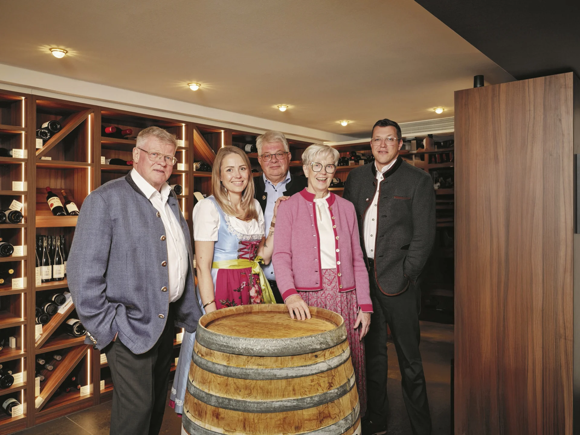 Fünf Personen in traditioneller Kleidung in einem Weinkeller vor einem Weinfass