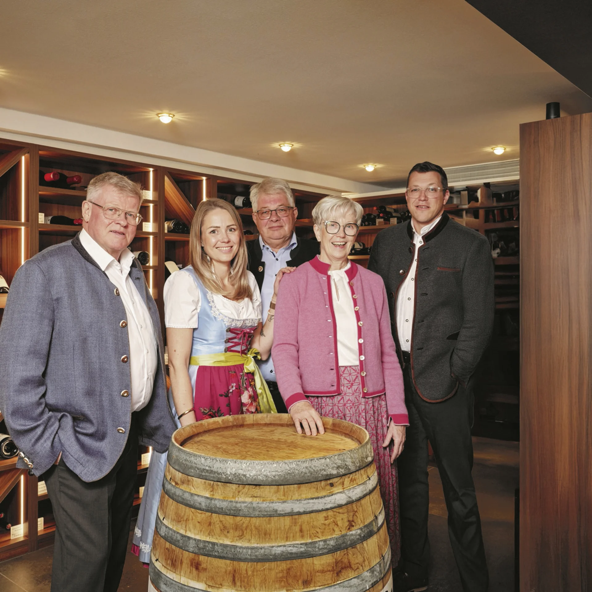 Fünf Personen in traditioneller Kleidung in einem Weinkeller vor einem Weinfass