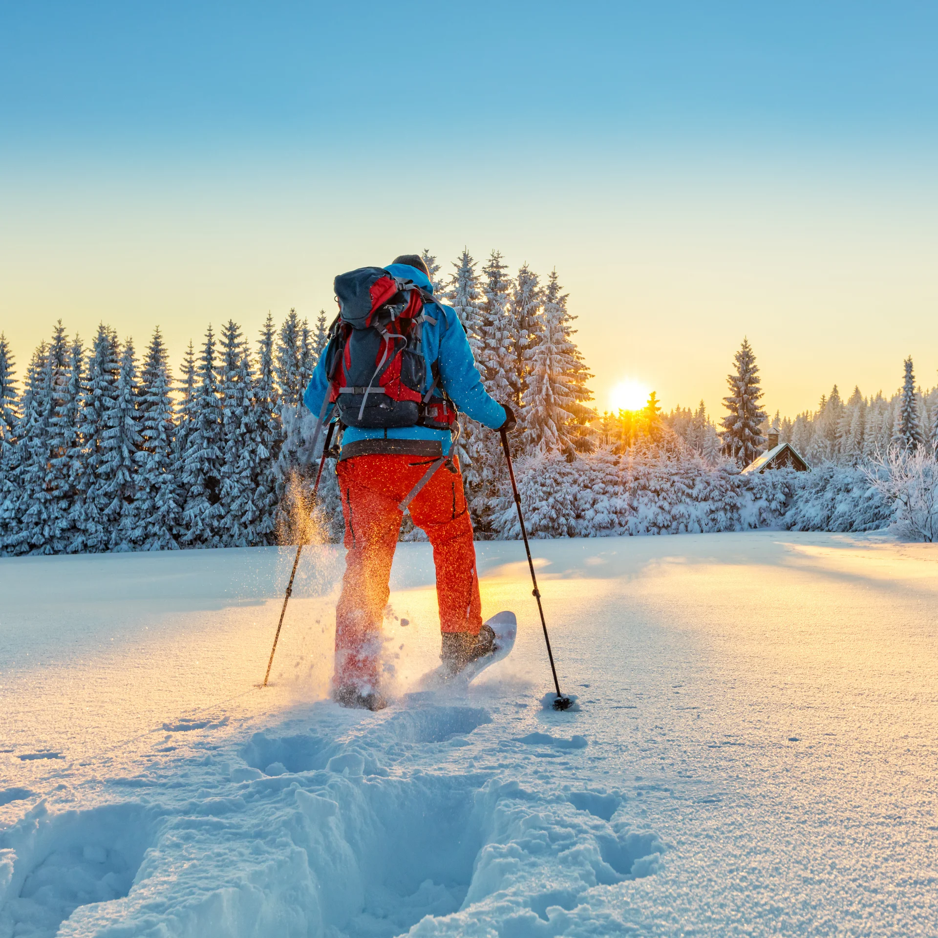 Person beim Skilanglauf in verschneiter Winterlandschaft beim Sonnenuntergang