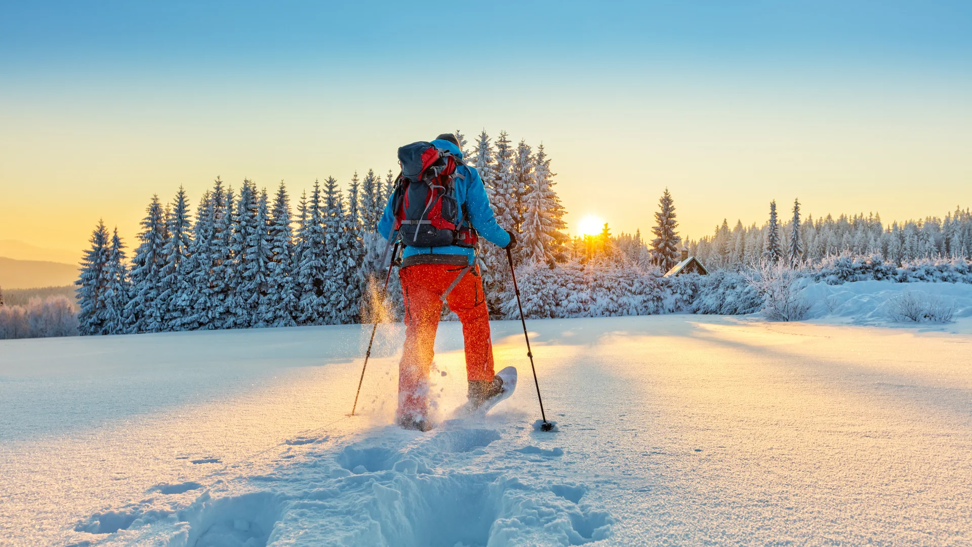 Person beim Skilanglauf in verschneiter Winterlandschaft beim Sonnenuntergang