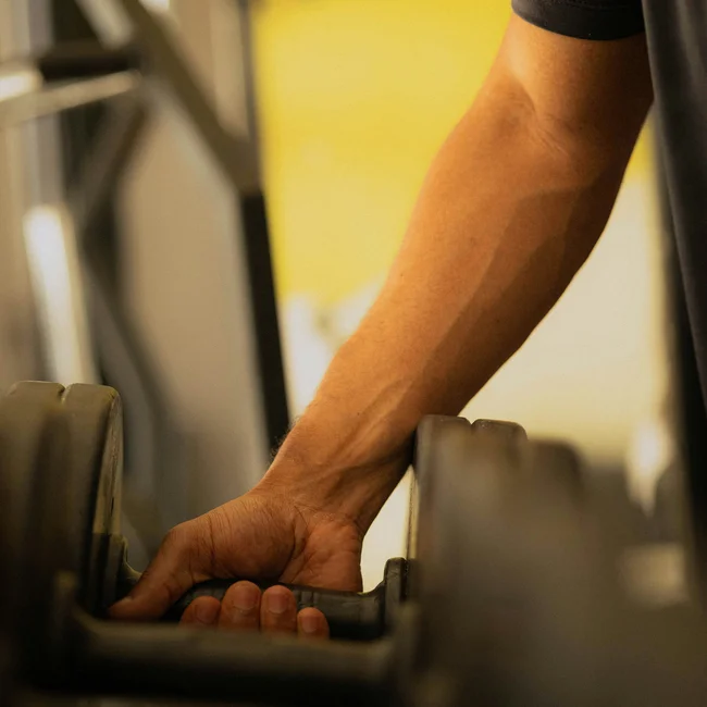 Homme attrapant un haltère sur un support dans une salle de sport