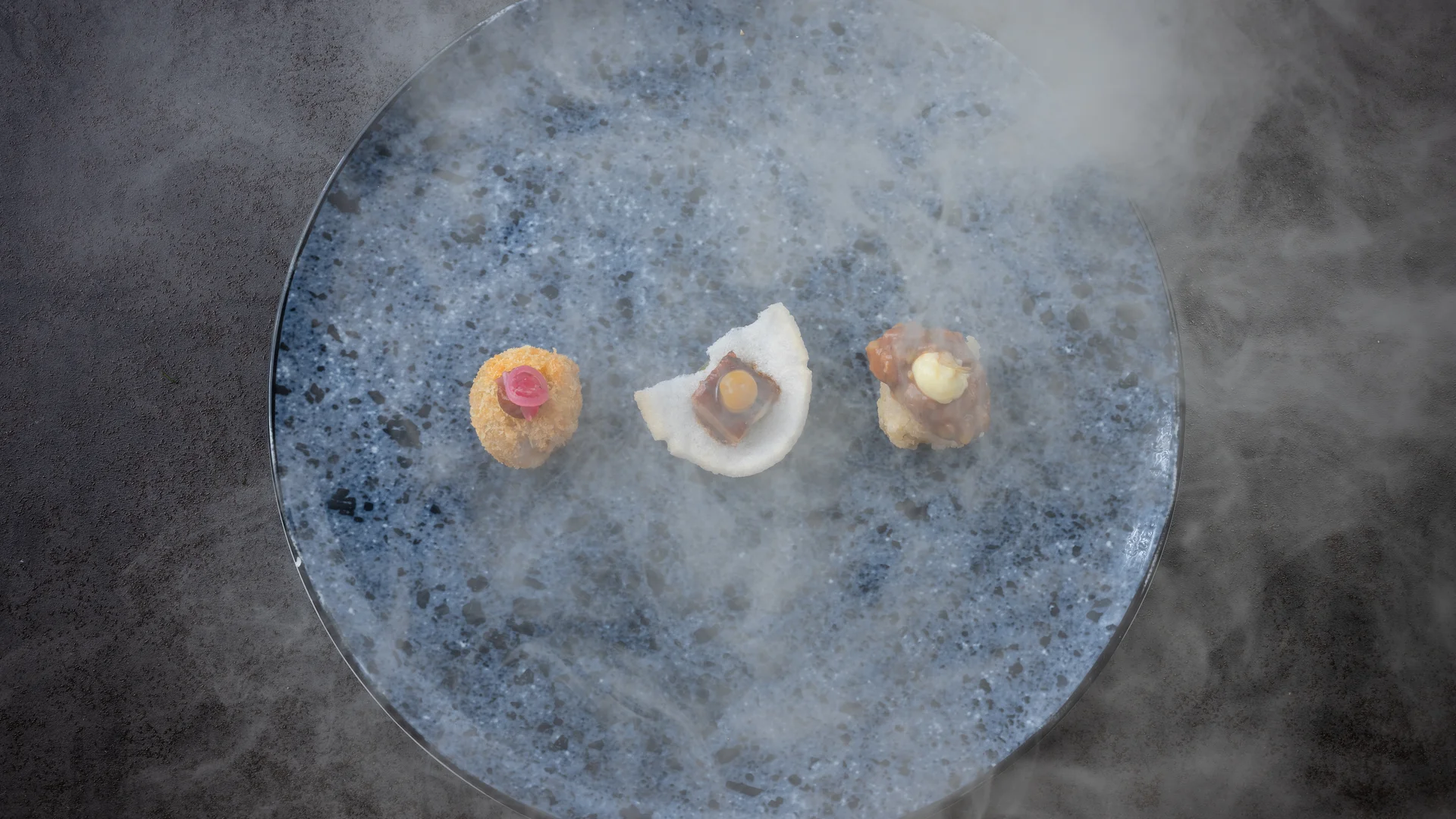 Drei unterschiedliche Appetithäppchen auf blauem Teller mit Nebel
