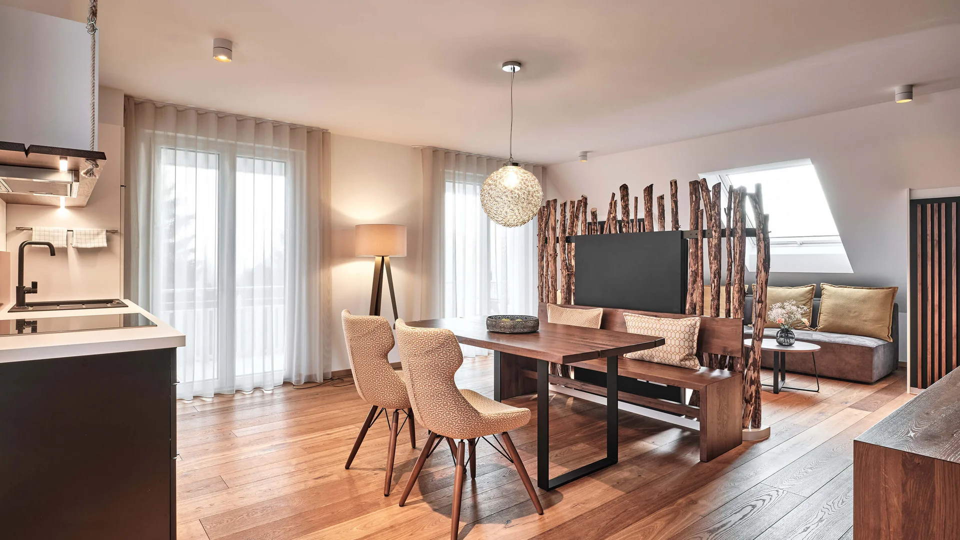 Heller Wohn- und Essbereich mit Küche, Holztisch, Sofa und Fernseher
