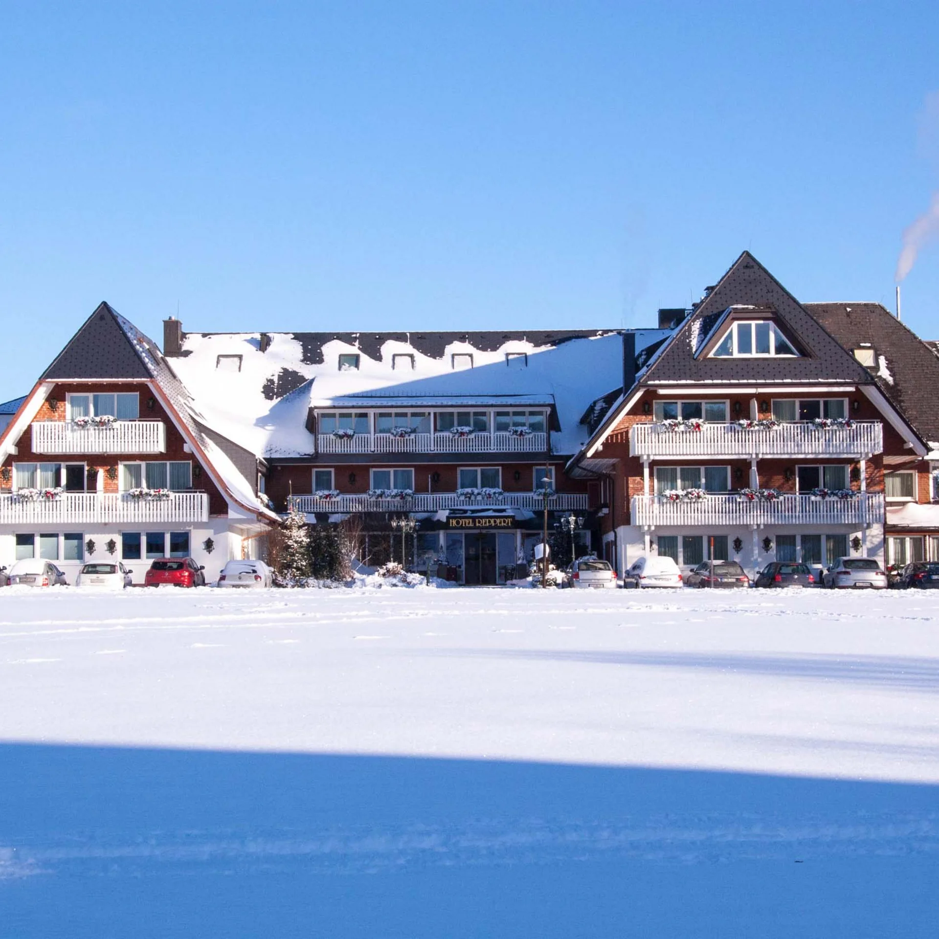 Hôtel au toit enneigé devant un vaste paysage couvert de neige