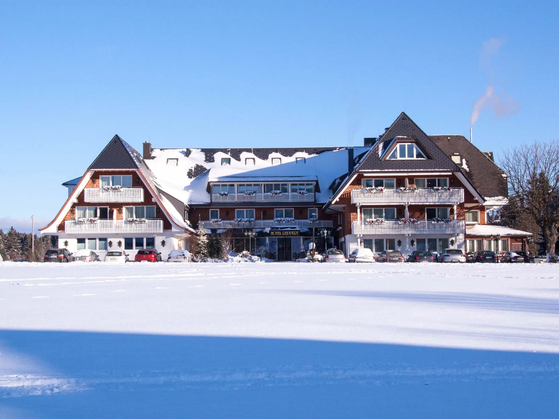 Hotel with a snow-covered roof beside a wide, snowy landscape
