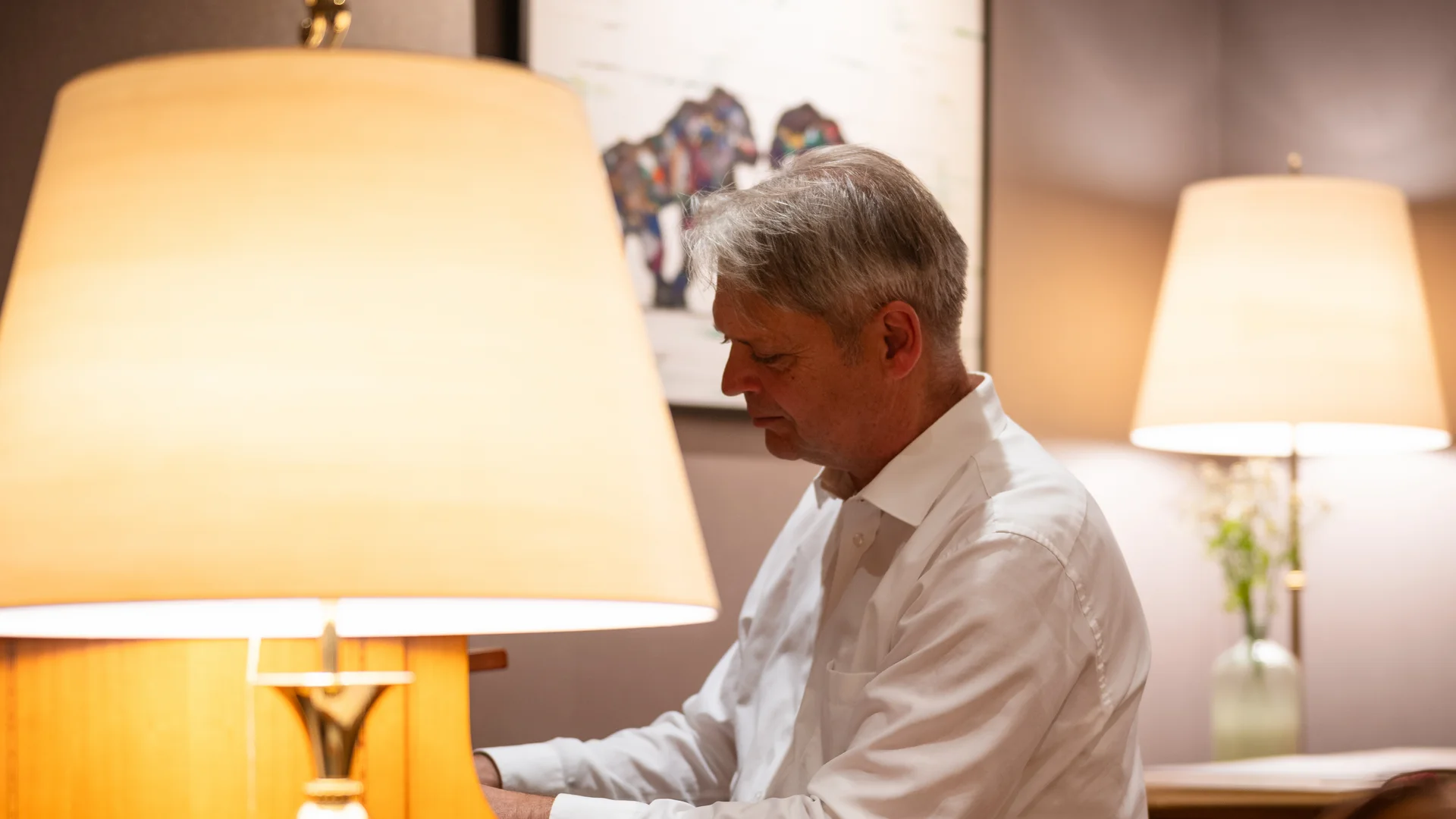 Mann spielt Klavier in einem gemütlichen Raum mit Lampen und Kunst an der Wand