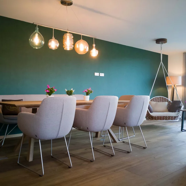 Moderner Essbereich mit Holztisch, hellen Stühlen, Pendelleuchten und Hängesessel