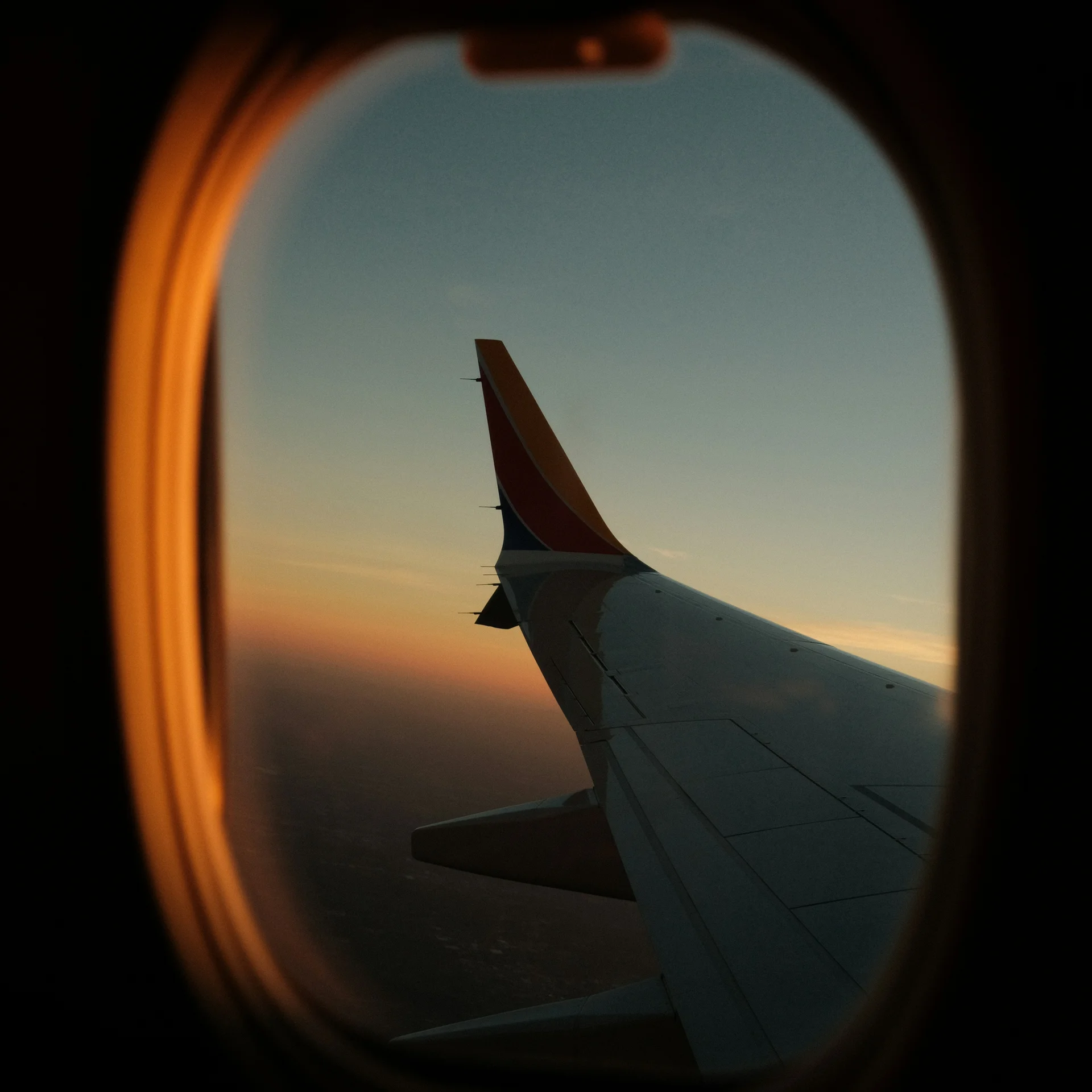 Blick aus dem Flugzeugfenster auf den Flügel bei Sonnenuntergang