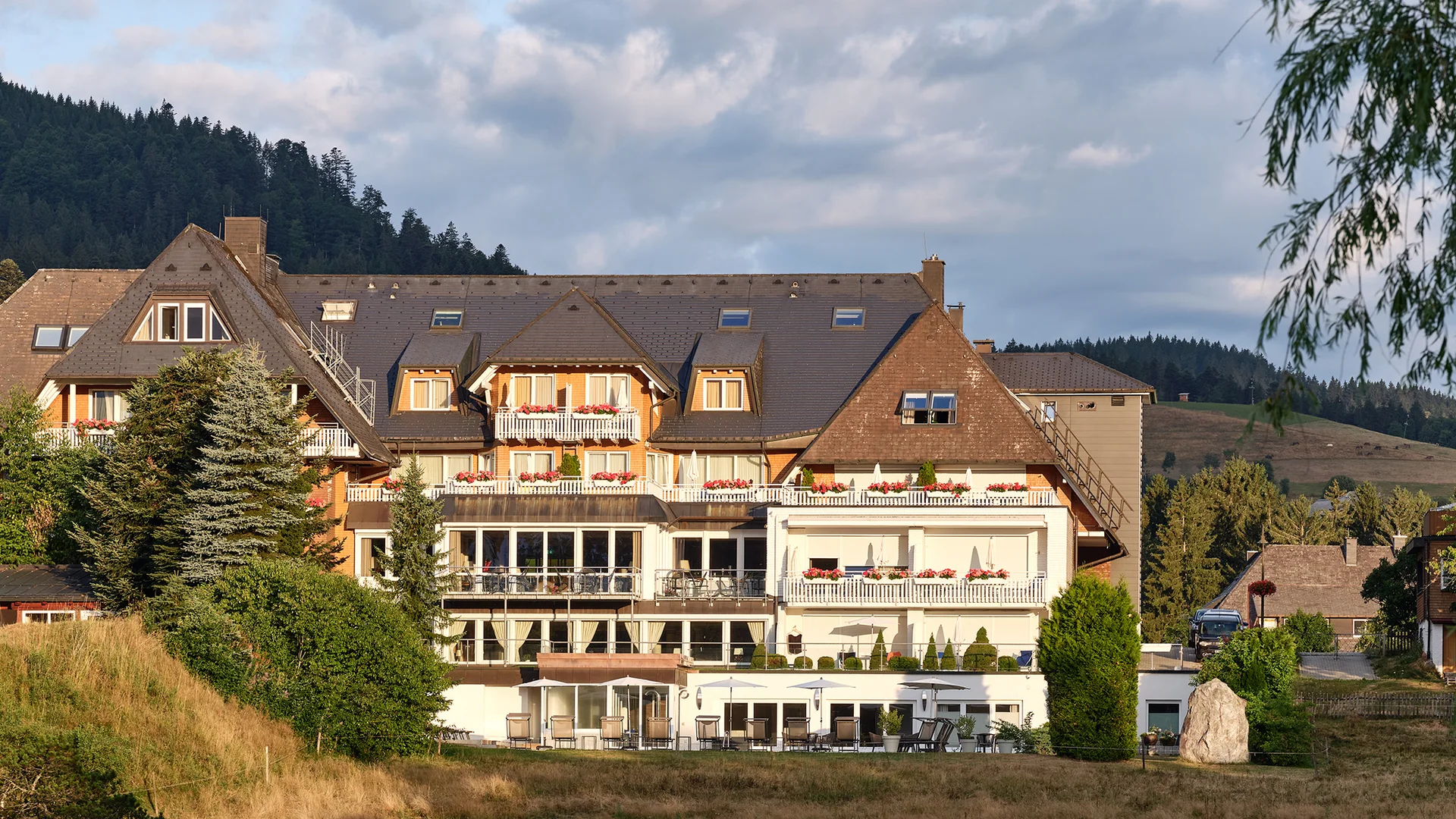 Hotelgebäude am See mit Spiegelung und Bergkulisse