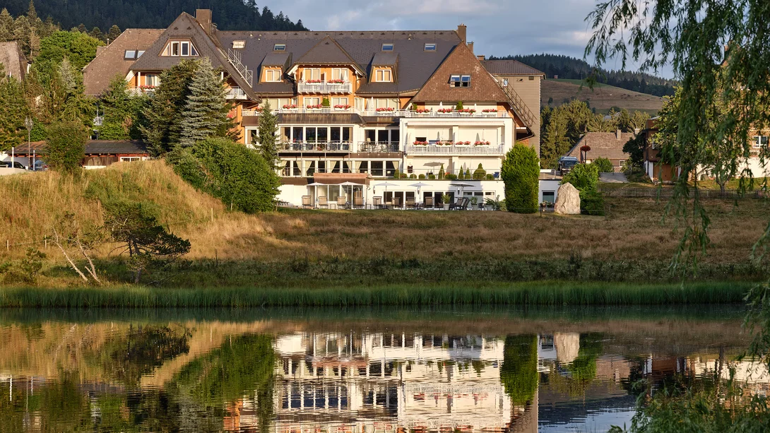 Hôtel au bord du lac avec reflet et montagnes en arrière-plan