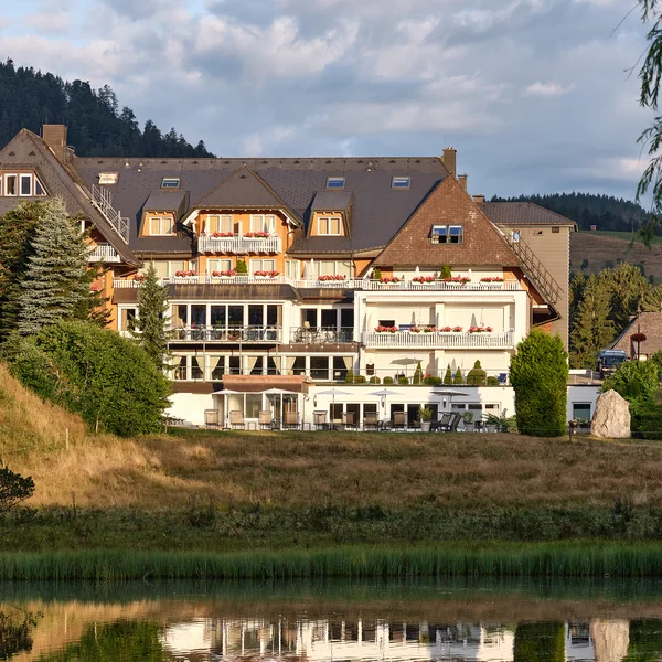 Hotelgebäude am See mit Spiegelung und Bergkulisse