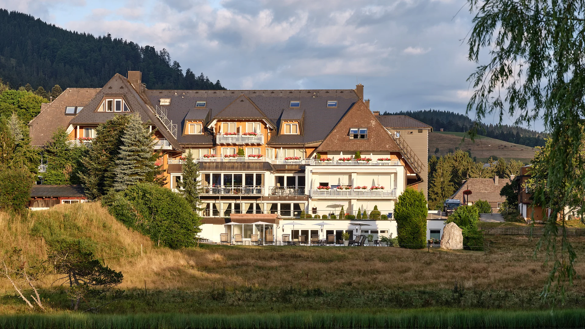 Hotelgebäude am See mit Spiegelung und Bergkulisse